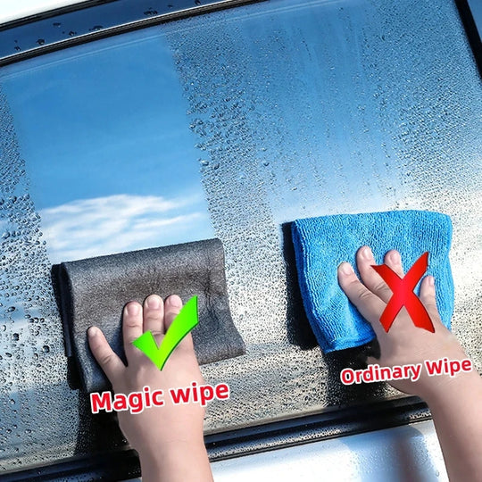 Hand wischt Glas mit grauem Mikrofasertuch für streifenfreie Fensterreinigung