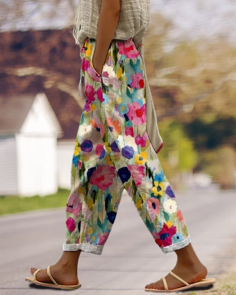 Weite Damenhose mit buntem Blumenmuster in Aquarell-Optik, lässiger Schnitt, umgekrempelte Hosenbeine, kombiniert mit flachen Sandalen