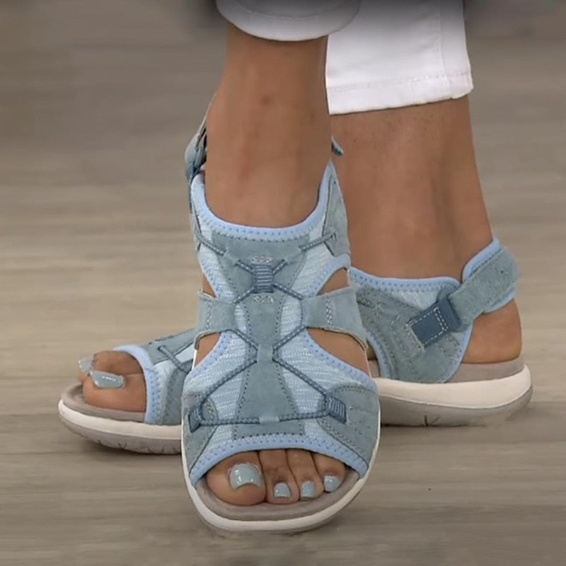 Bequeme blaue Sportsandalen für Damen mit weißen Sohlen, getragen zu weißen Hosen