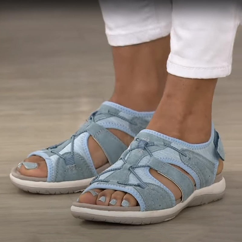 Bequeme blaue Sportsandalen für Damen mit weißen Sohlen, getragen zu weißen Hosen