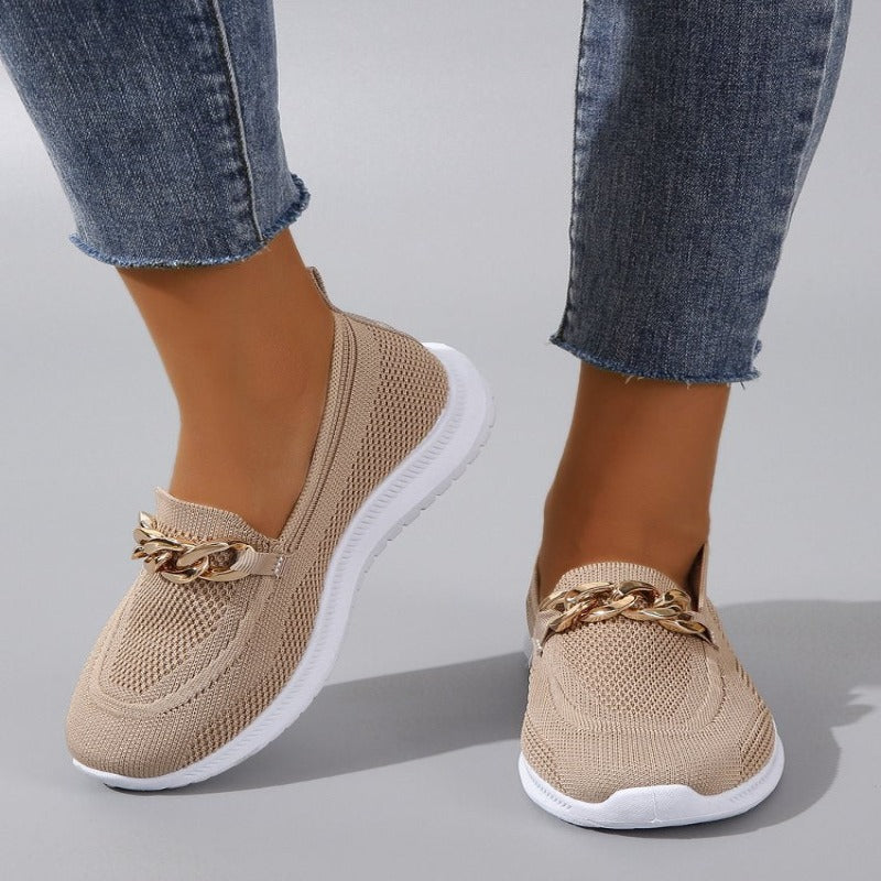Weiße Damen-Slip-On-Sneaker mit goldener Gliederkette, atmungsaktivem Strickmaterial und weißer Sohle, kombiniert mit blauen Jeans