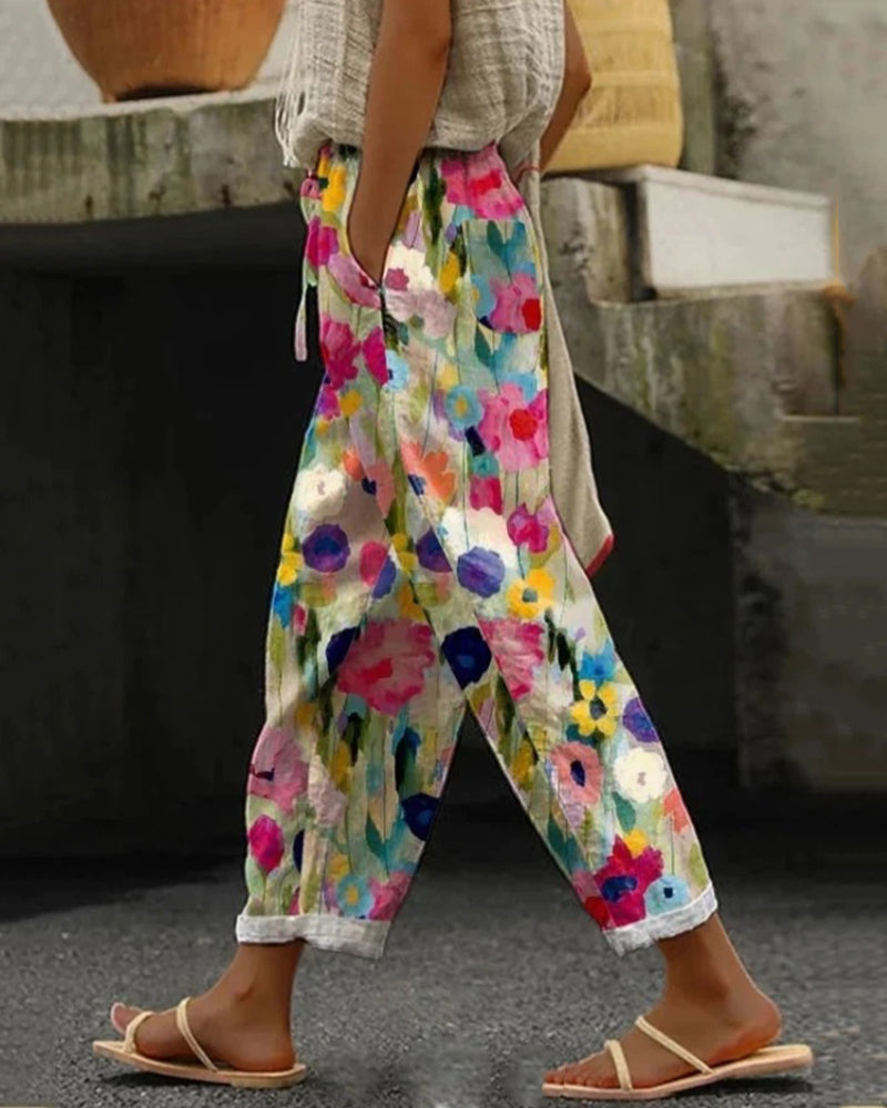 Weite Damenhose mit buntem Blumenmuster in Aquarell-Optik, lässiger Schnitt, umgekrempelte Hosenbeine, kombiniert mit flachen Sandalen