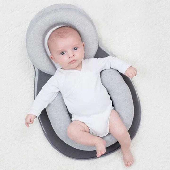 Baby liegt auf ergonomischem Babykissen in Grau – Kopf- und Rückenstütze für sicheren Schlafkomfort