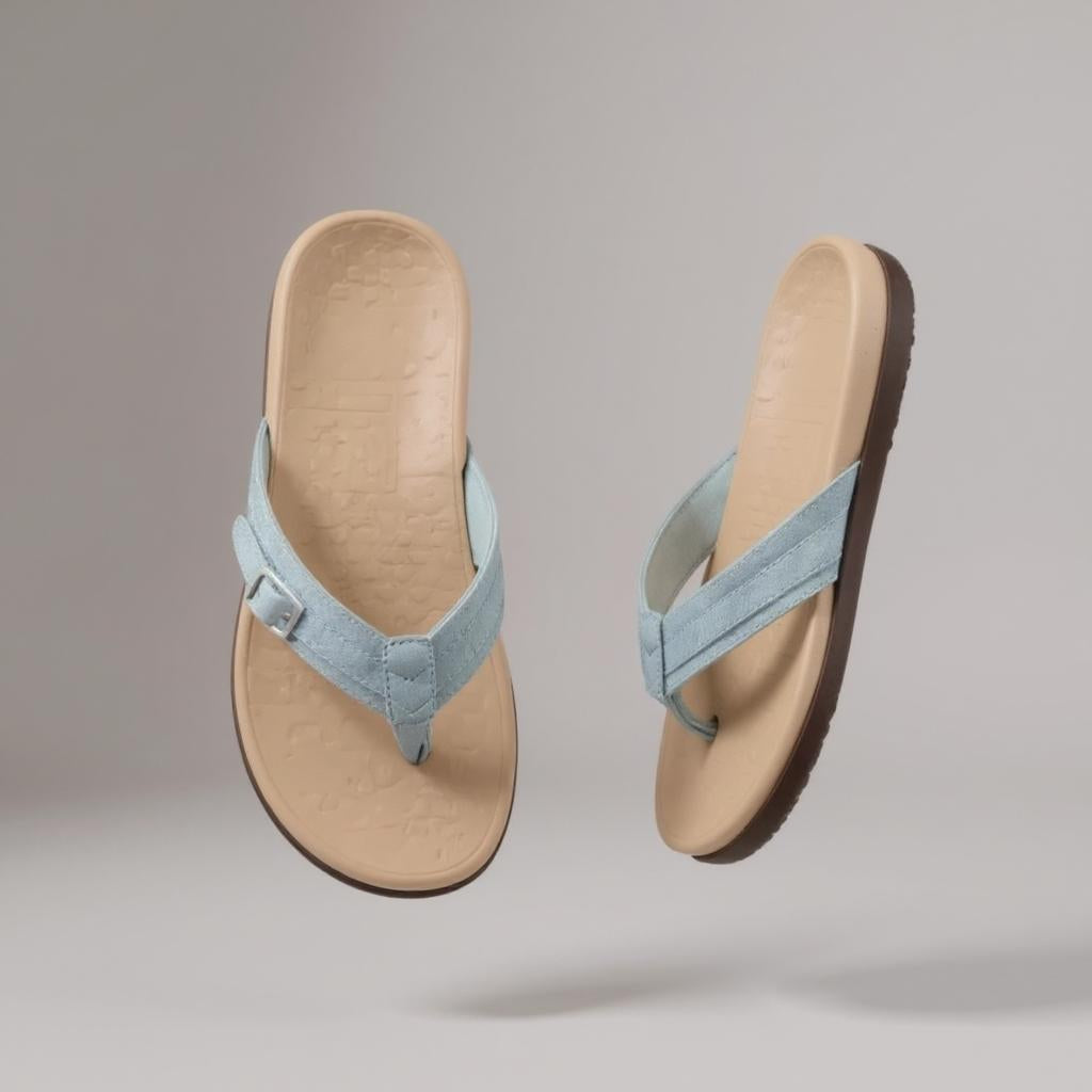 Ein Paar rosafarbene Zehensandalen mit Schnalle, beigefarbenem Fußbett und brauner Sohle, schwebend vor grauem Hintergrund.