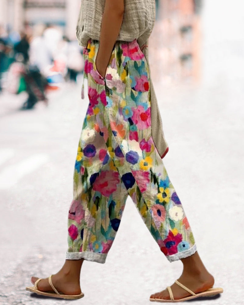 Weite Damenhose mit buntem Blumenmuster in Aquarell-Optik, lässiger Schnitt, umgekrempelte Hosenbeine, kombiniert mit flachen Sandalen