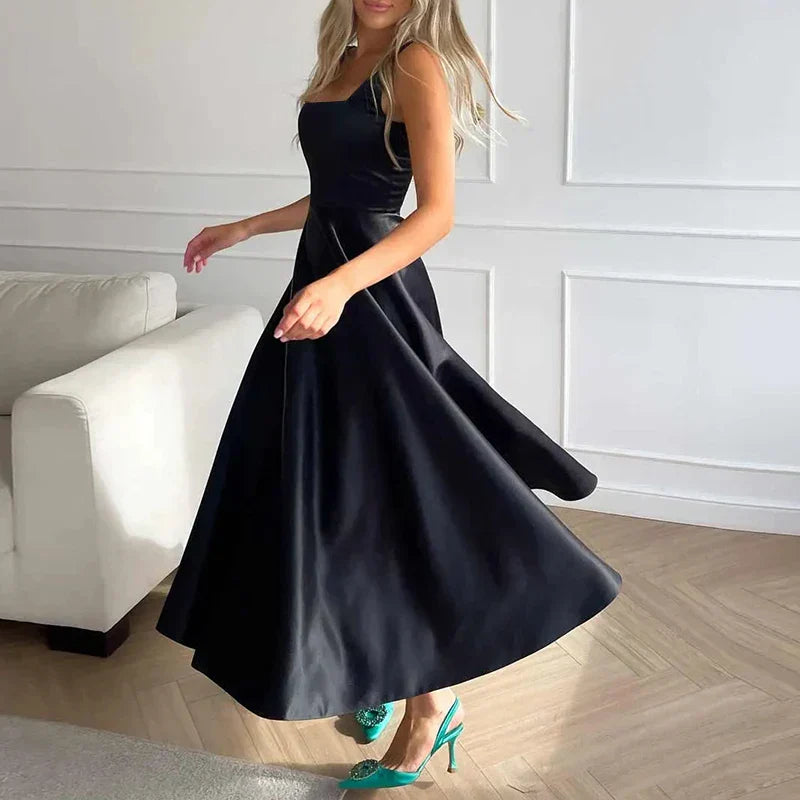 Elegantes schwarzes Abendkleid mit weitem Rock und grünen High Heels im modernen Wohnzimmer
